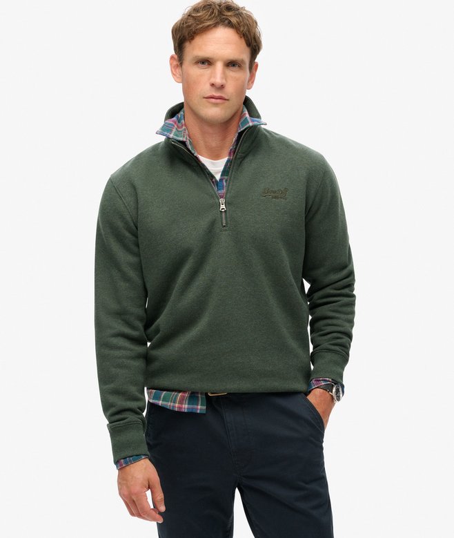 Man wearing a green pullover with plaid shirt underneath on a white background