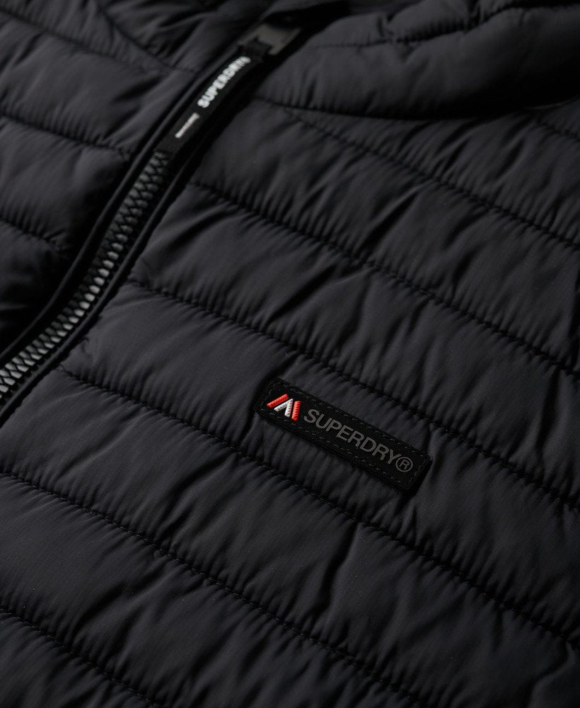 Close-up of a black puffer jacket with Superdry logo on a dark background