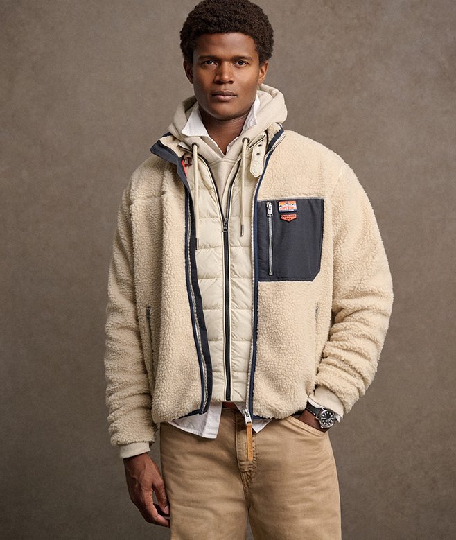 Man wearing a beige fleece jacket with a brown background