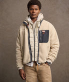 Man wearing a beige fleece jacket with a brown background