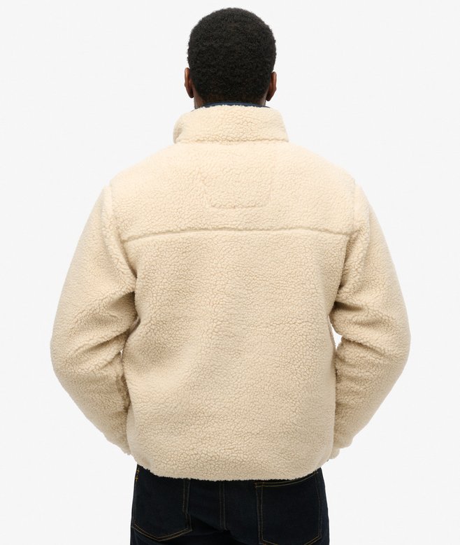 Person wearing a beige fleece jacket on a white background