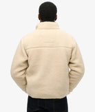 Person wearing a beige fleece jacket on a white background