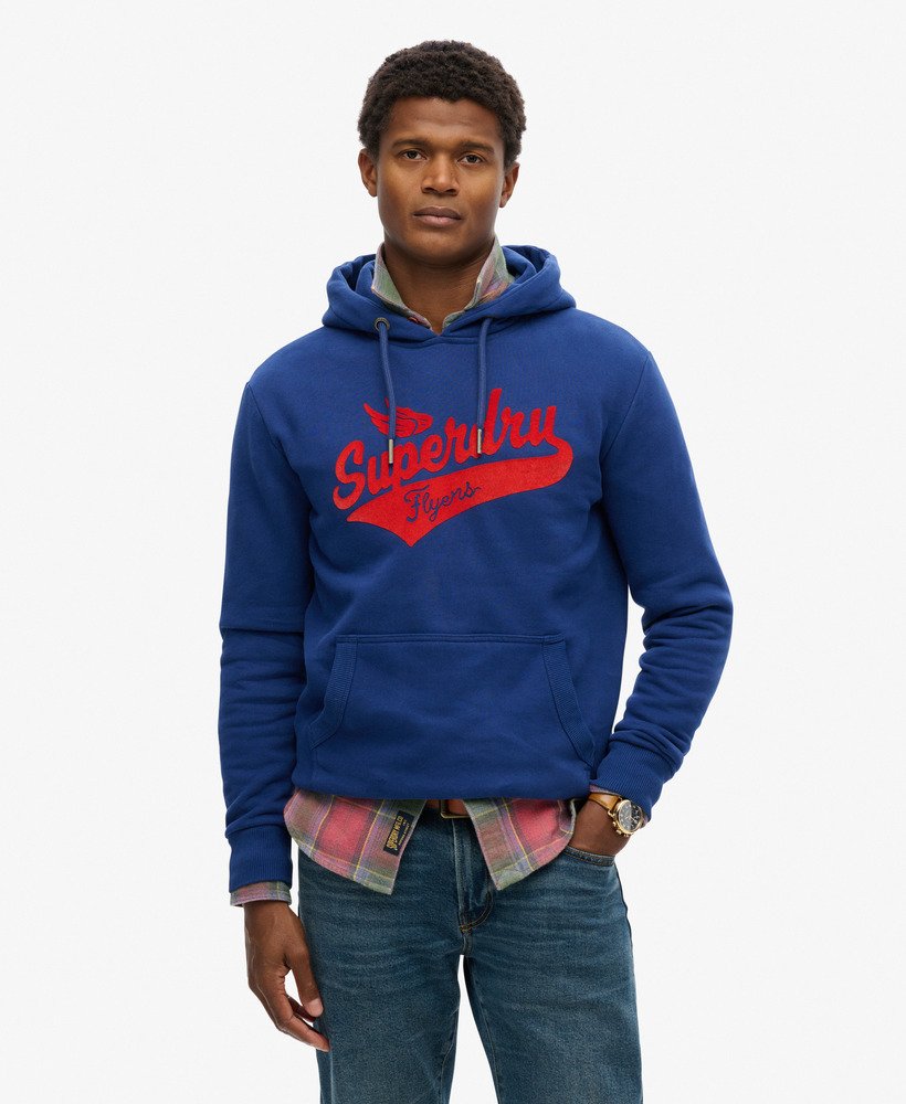 Man wearing a navy blue hoodie with a Superdry flyers script longo on the front