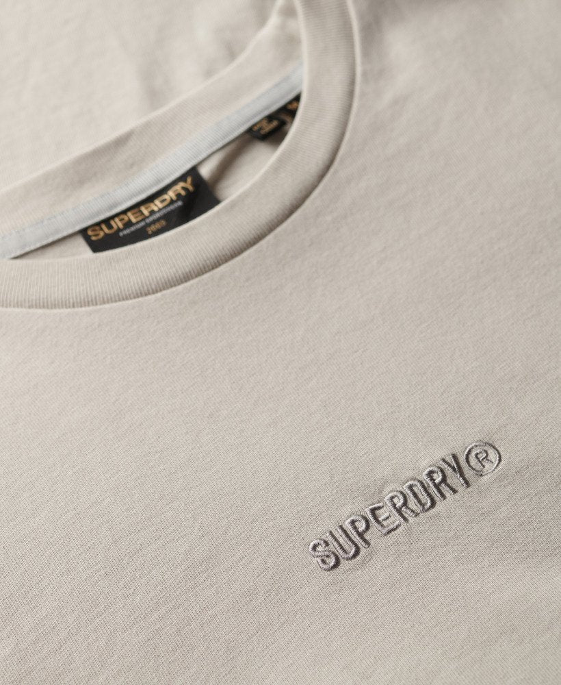 Close-up of a beige Superdry t-shirt with branding details.