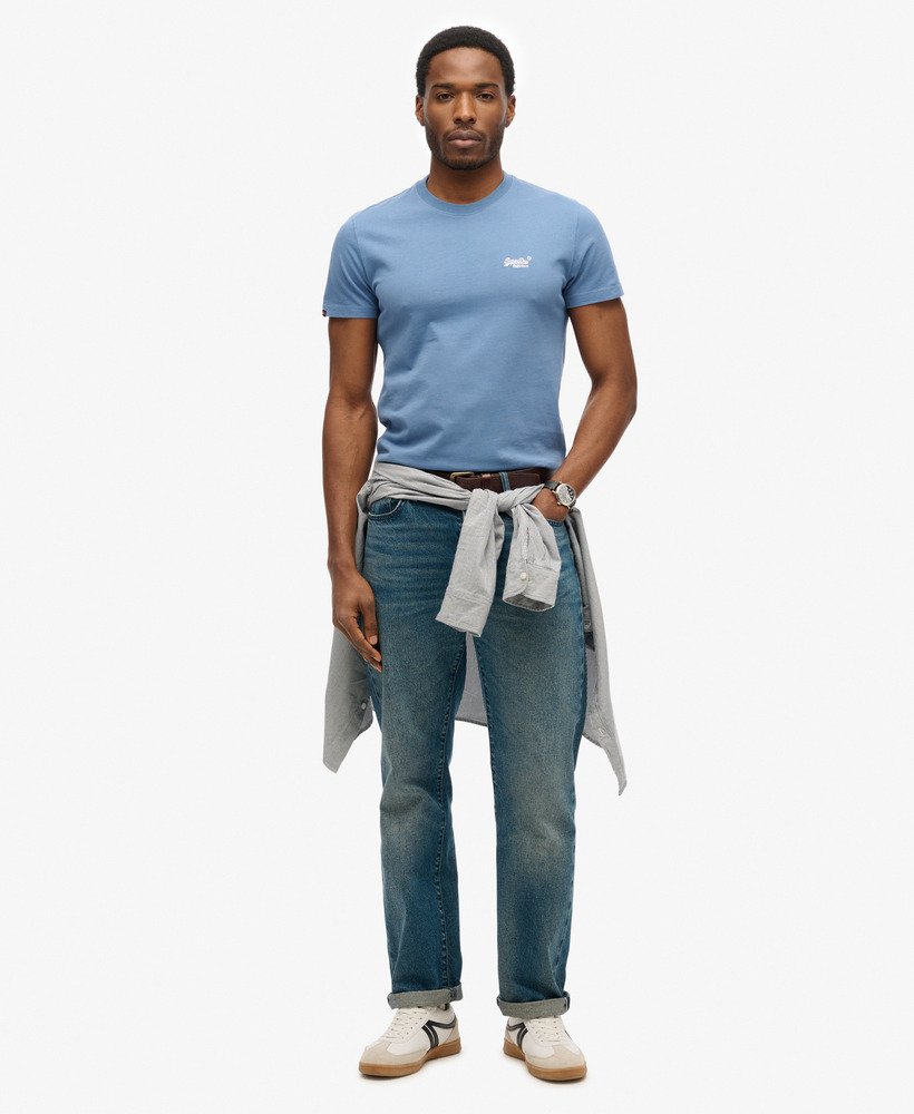 Man wearing a blue t-shirt and jeans with a white background
