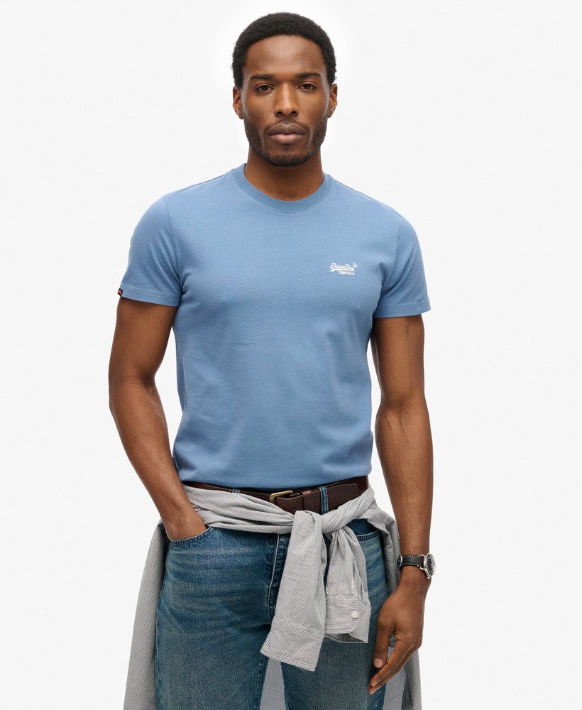 Man wearing a light blue t-shirt with a logo on a white background
