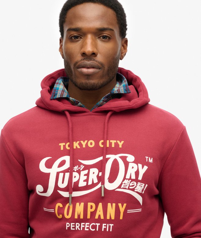 Man wearing a red Superdry hoodie with visible branding on a white background
