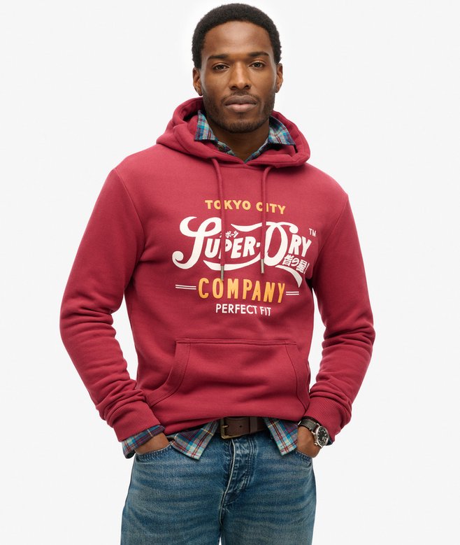 Man wearing a red hoodie with 'Superdry' branding on a white background