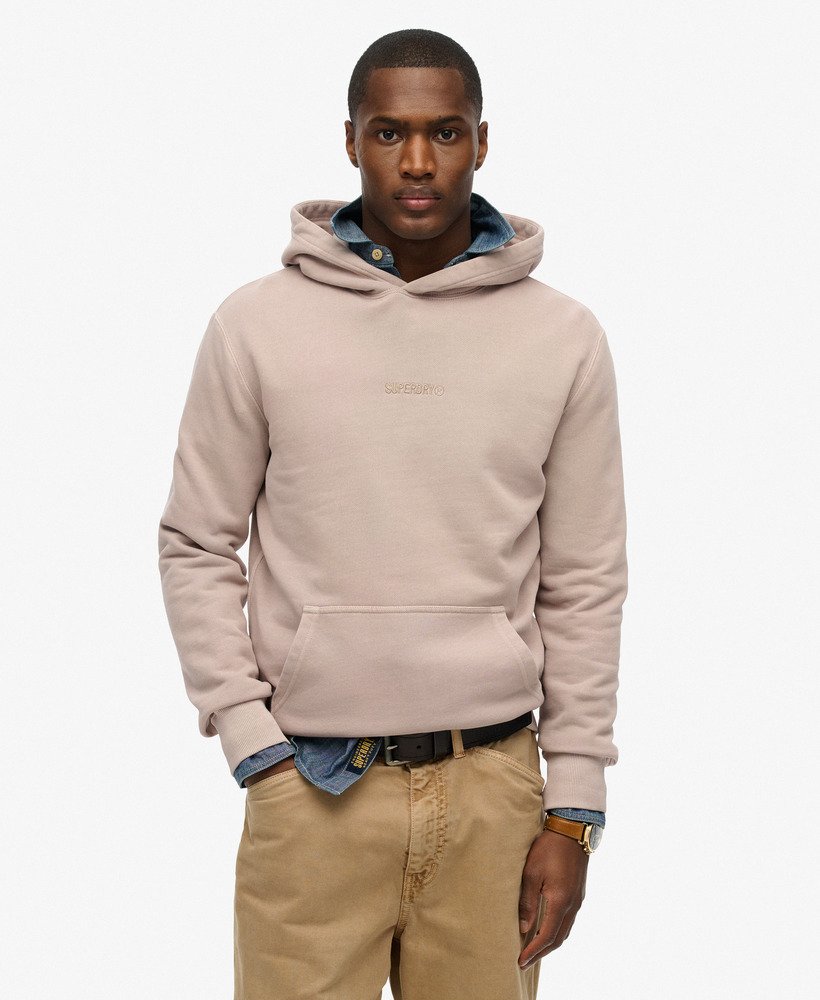 Man wearing a beige hoodie with a visible brand logo on a white background