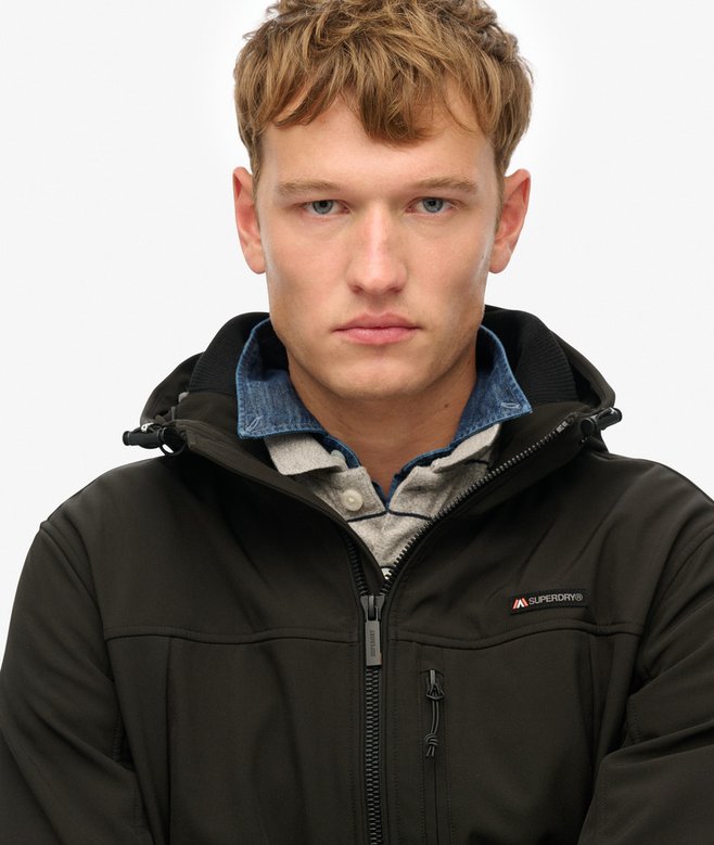 Man wearing a black jacket with a visible brand logo on a white background