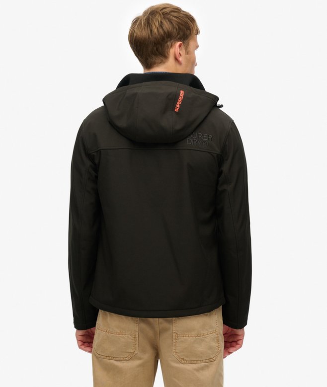 Person wearing a black jacket with a brand logo on the back against a white background