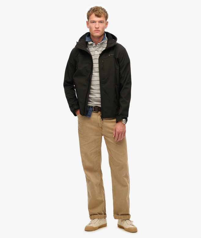 Man wearing a black jacket, striped shirt, and beige pants on a white background