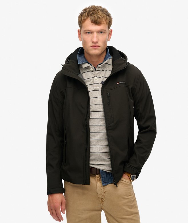 Man wearing a black jacket over a striped shirt with a white background