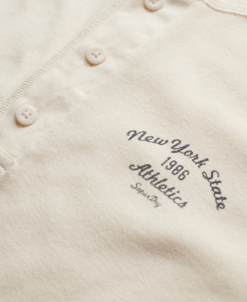 Close-up of a beige fabric with 'New York State Athletics 1986' text embroidered on it.