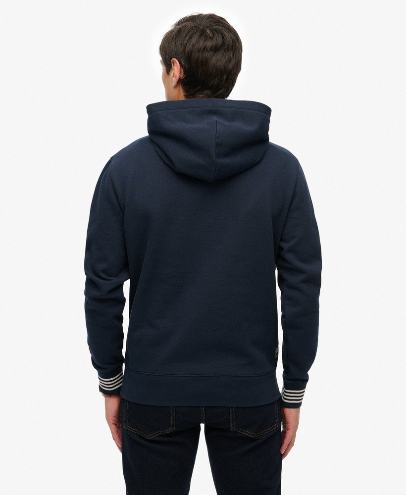 Person wearing a navy blue hoodie with striped cuffs on a white background