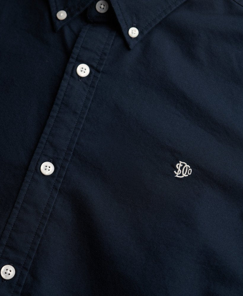 Navy blue shirt with white buttons and a logo on the chest.