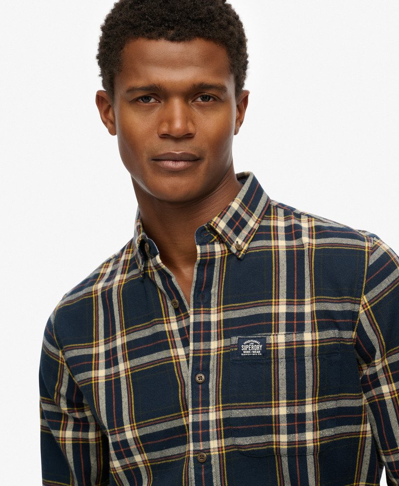 Man wearing a plaid shirt with a visible brand logo on a white background