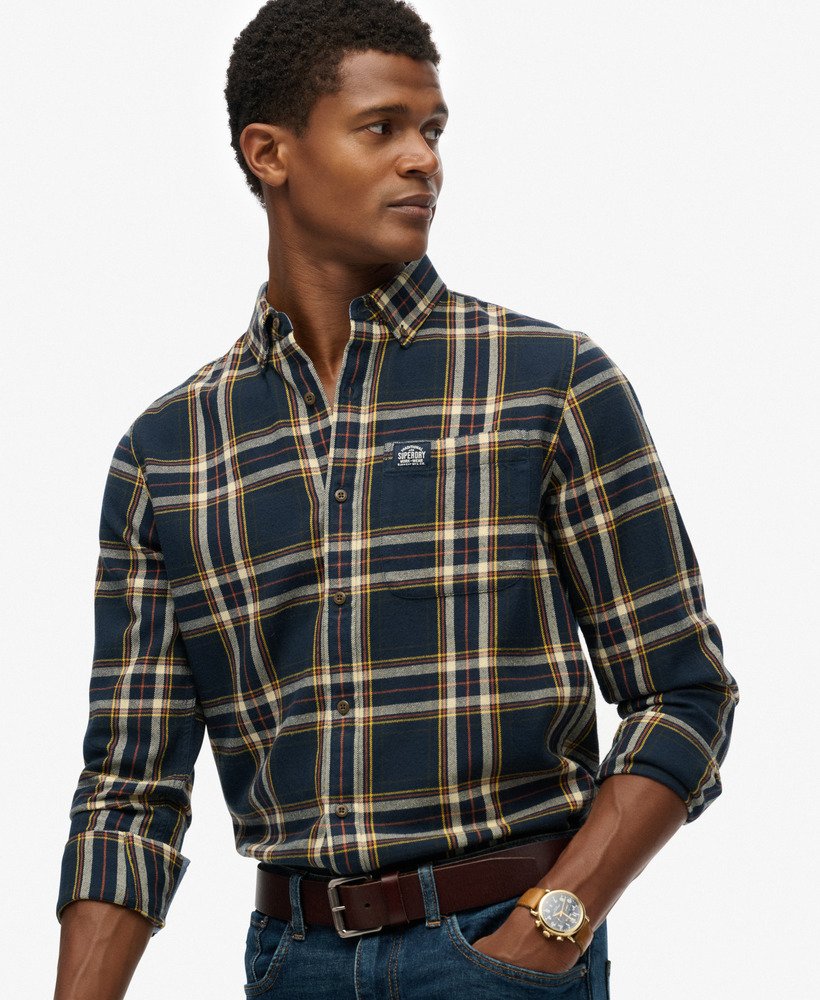 Man wearing a plaid shirt with a visible brand logo on a white background
