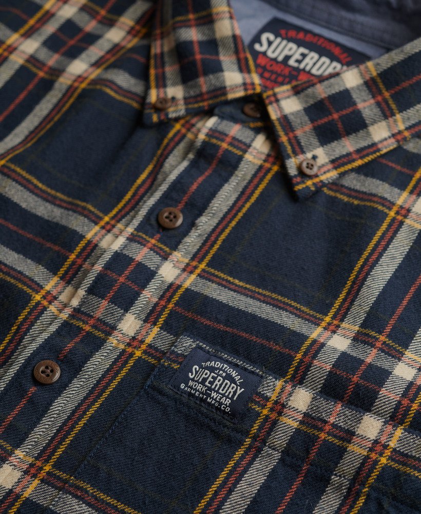 Close-up of a navy and yellow plaid shirt with Superdry branding on a dark background