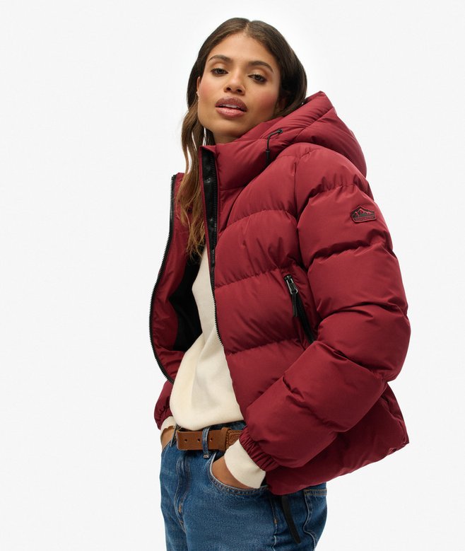 Woman wearing a red puffer jacket on a white background