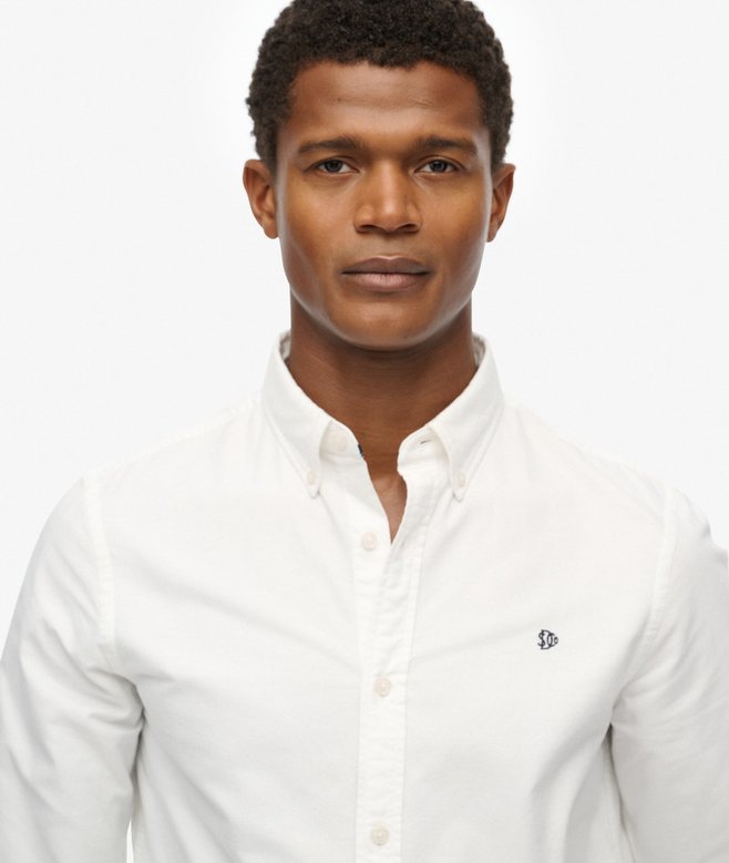 Man wearing a white button-up shirt on a plain background