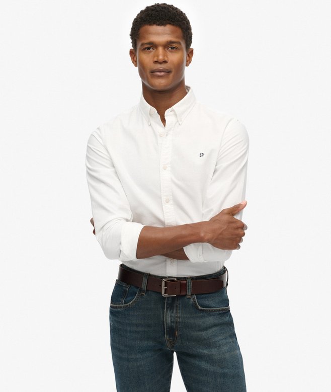 Man wearing a white shirt and blue jeans on a plain background