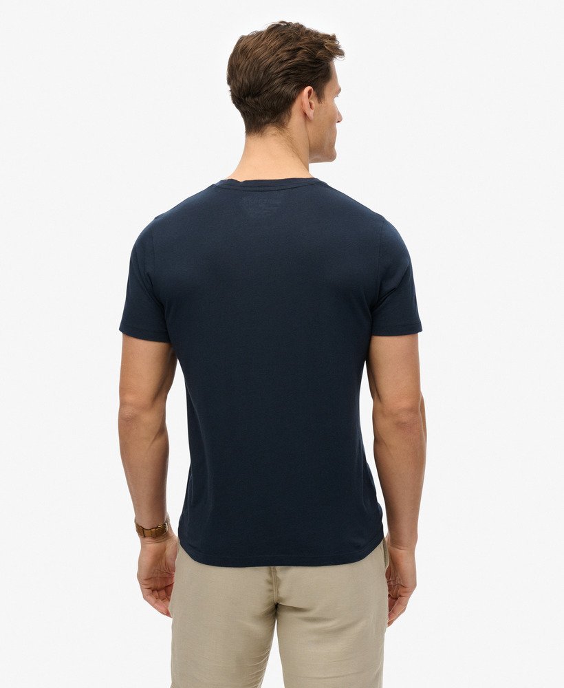 Man wearing a navy blue t-shirt and beige pants on a white background