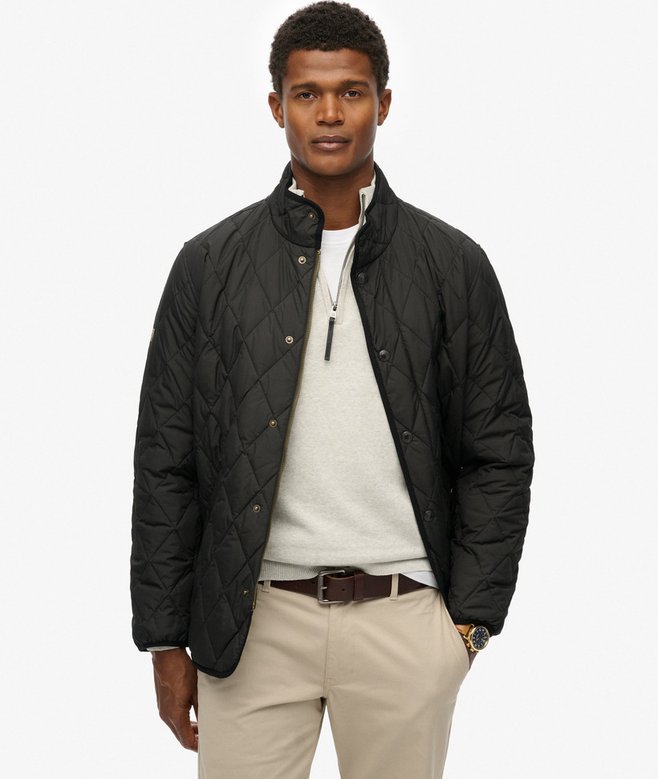 Man wearing a black quilted jacket over a white shirt on a white background