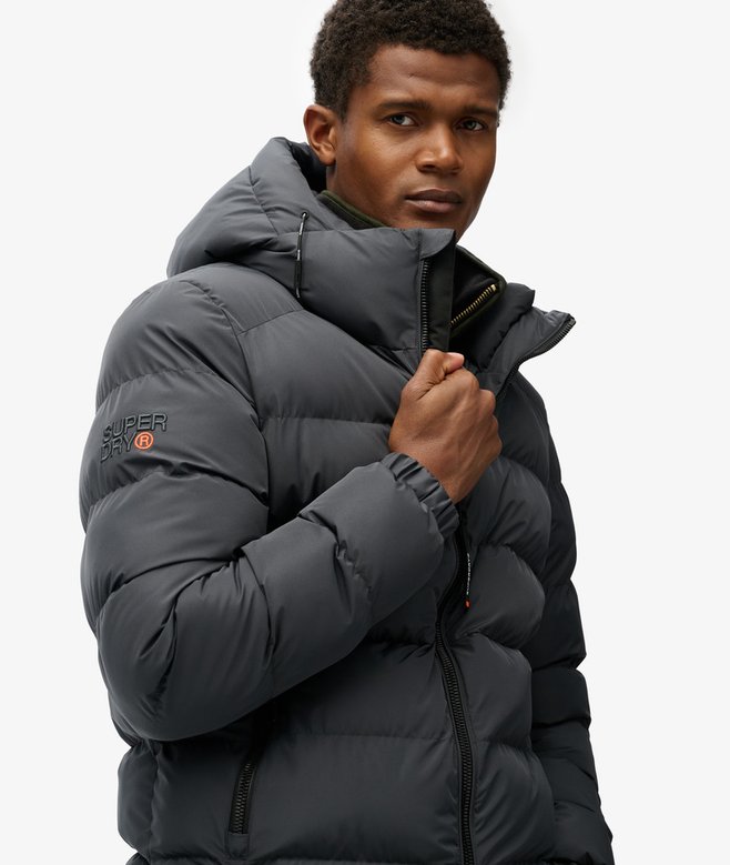 Man wearing a gray puffer jacket with a visible brand logo on a white background
