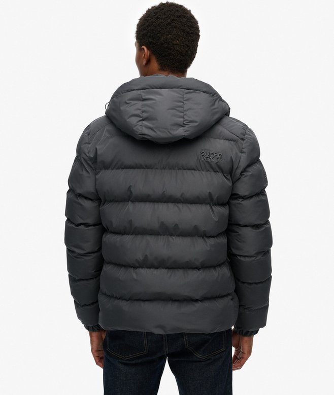 Person wearing a dark gray puffer jacket on a white background