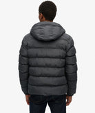Person wearing a dark gray puffer jacket on a white background