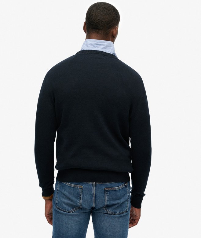 Man wearing a navy sweater and blue jeans on a white background