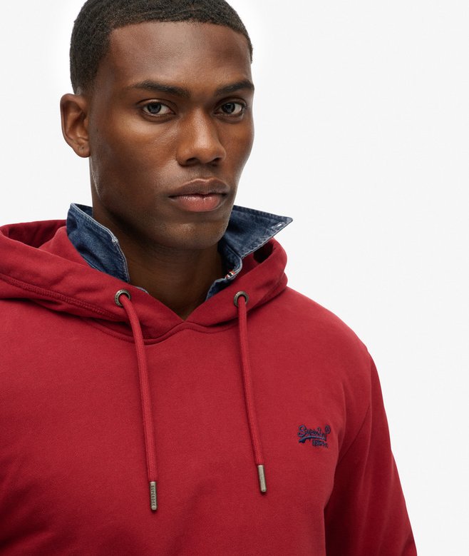 Man wearing a red hoodie with a brand logo on a plain background