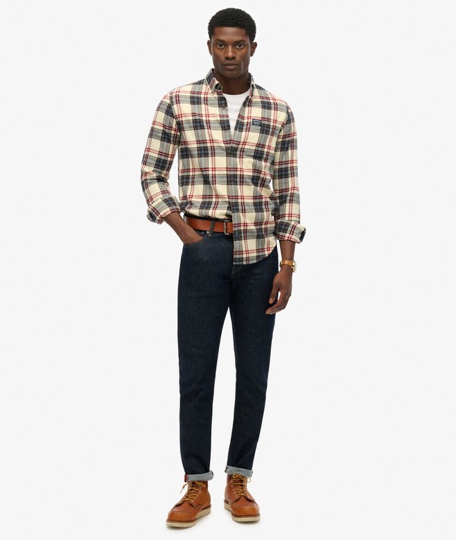 Man wearing a plaid shirt, jeans, and brown boots on a white background