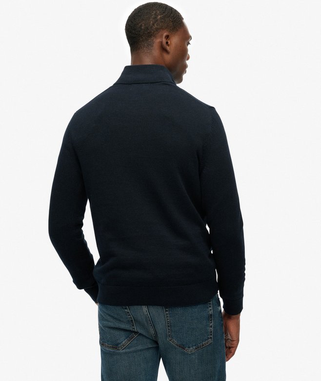 Man wearing a dark blue sweater and jeans on a white background