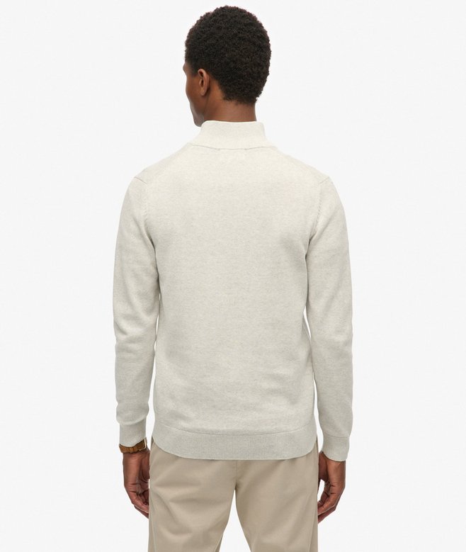 Man wearing a light gray sweater and beige pants on a white background
