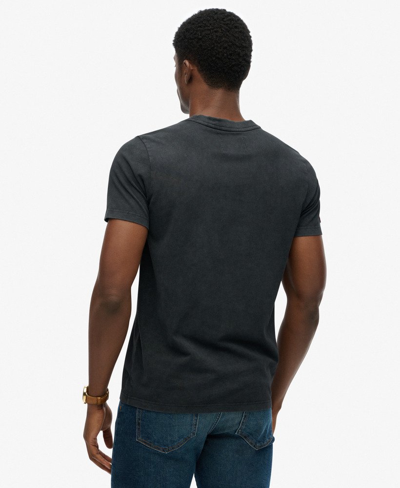 Man wearing a dark gray t-shirt and blue jeans on a white background