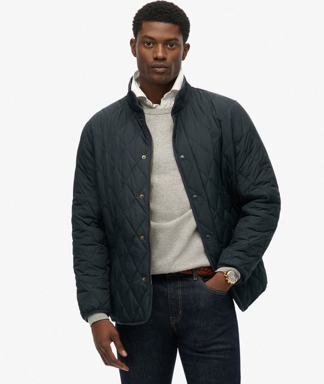 Man wearing a navy quilted jacket over a light shirt on a white background