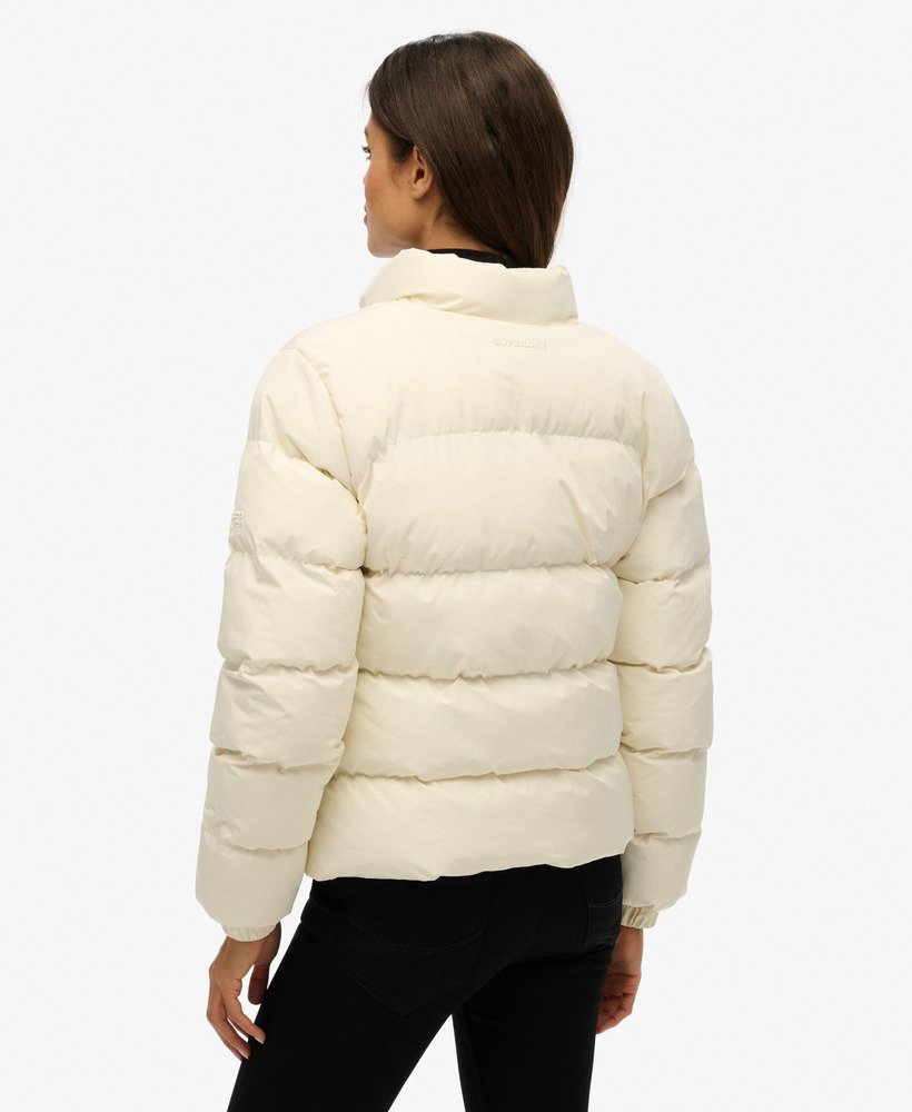 Person wearing a cream puffer jacket on a white background-Back view