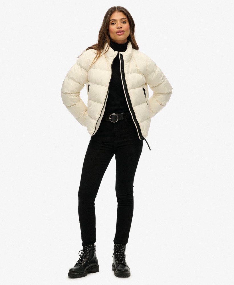 Woman wearing a white puffer jacket over a black outfit on a white background