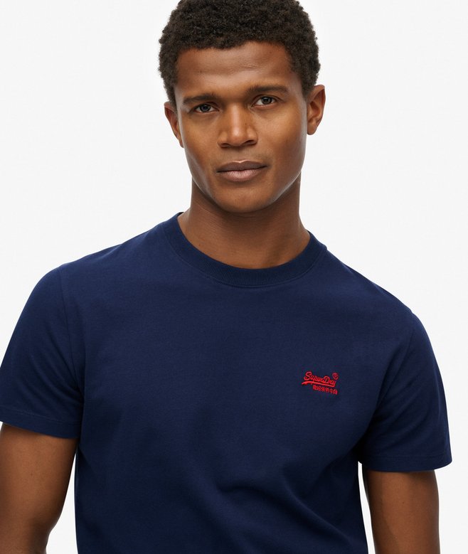 Man wearing a navy blue t-shirt with a red logo on a white background