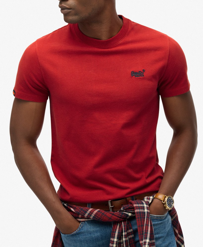 Person wearing a red t-shirt with a brand logo on a plain background