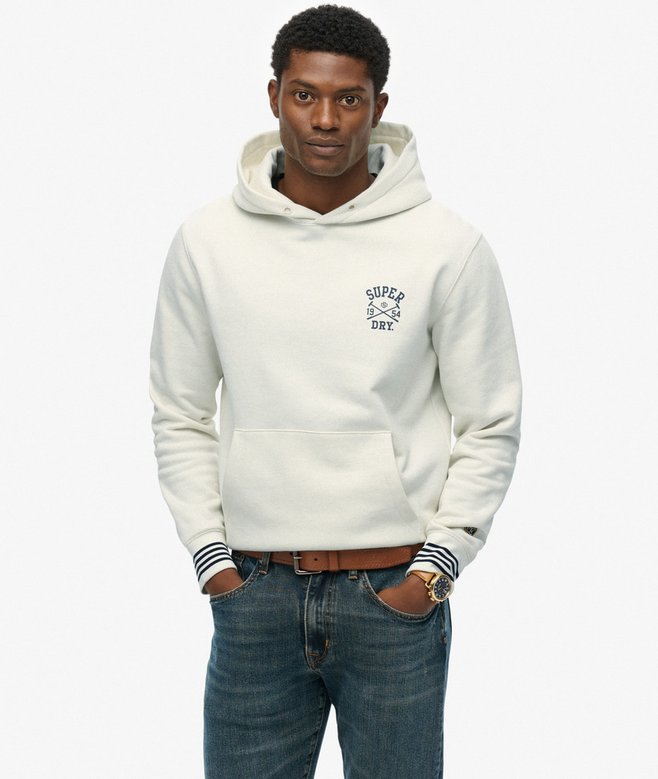Man wearing a white hoodie with a logo and blue jeans on a white background