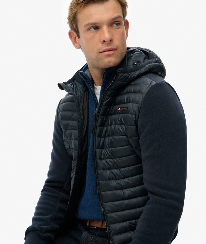 Man wearing a dark blue puffer vest over a navy jacket on a white background