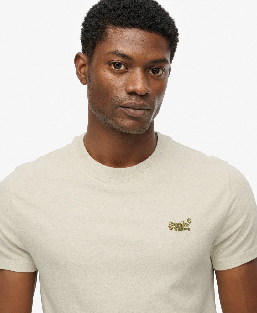 Man wearing a beige t-shirt with a logo on a white background