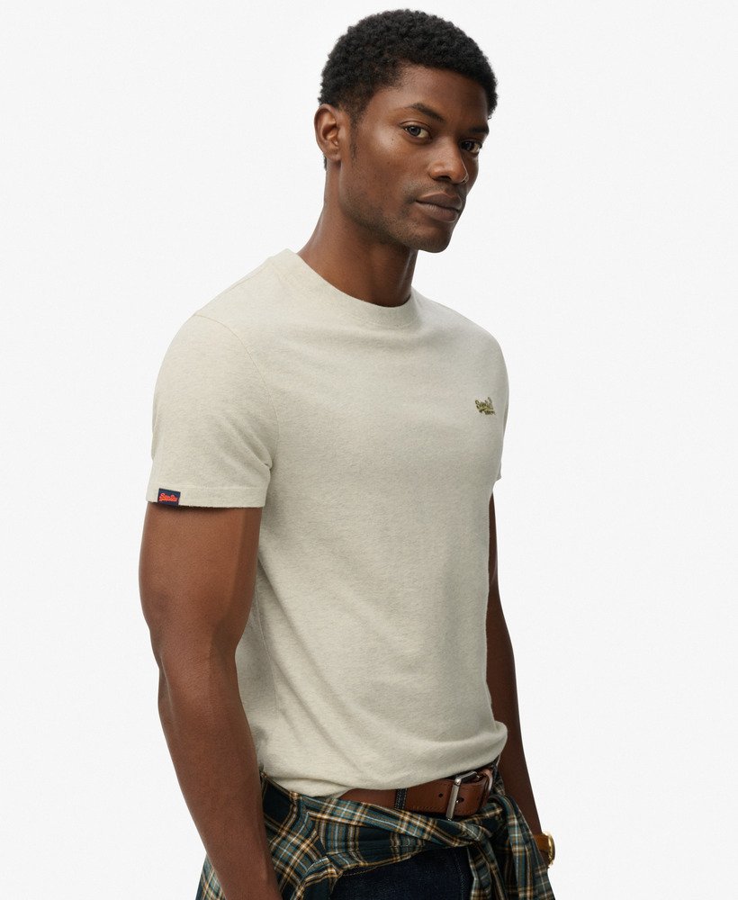 Man wearing a beige t-shirt with a logo on a white background