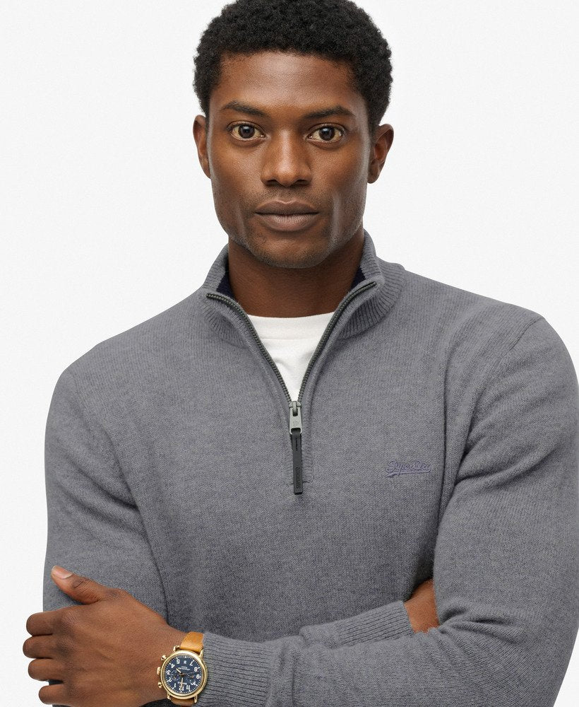 Man wearing a gray sweater with a brand logo on a white background