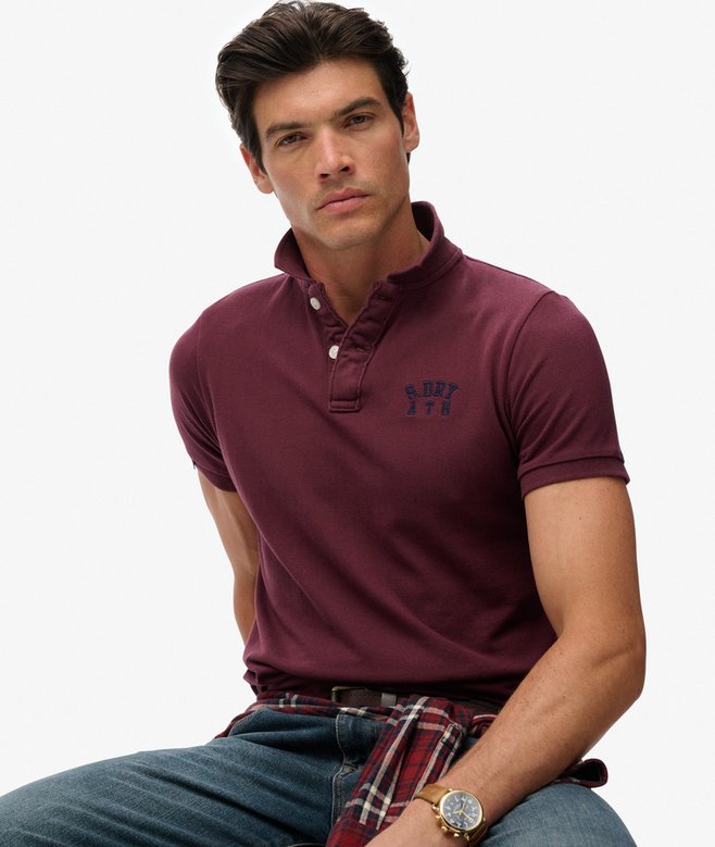 Man wearing a maroon polo shirt with a visible brand logo on a white background