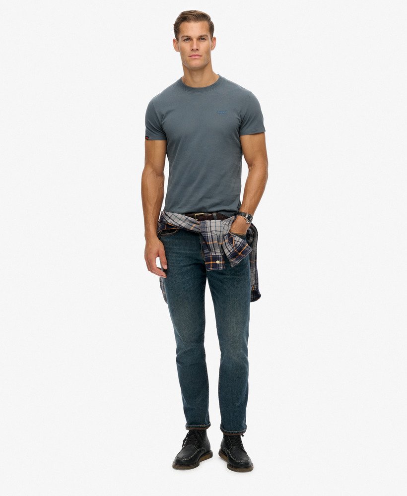 Man wearing a gray t-shirt, blue jeans, and black shoes on a white background