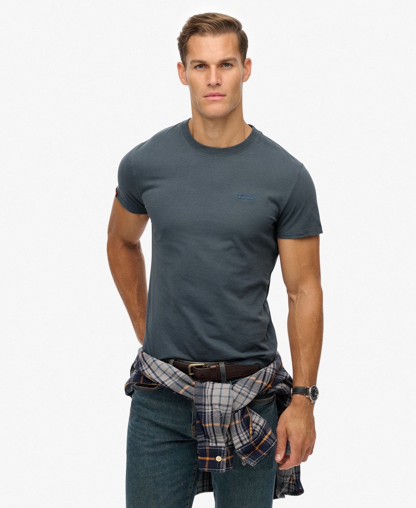 Man wearing a gray t-shirt and plaid shirt over jeans on a white background